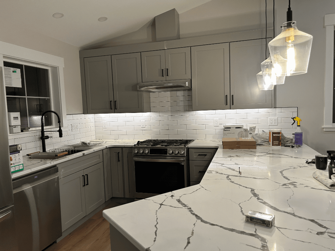 Modern kitchen with marble countertops and lighting.